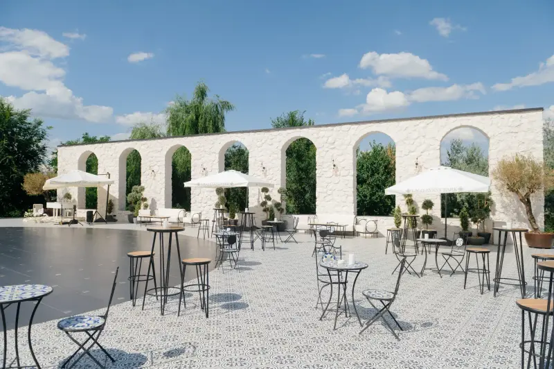 Curtea Lago Event Park, cu arcade din piatră albă, umbrele și mese înalte