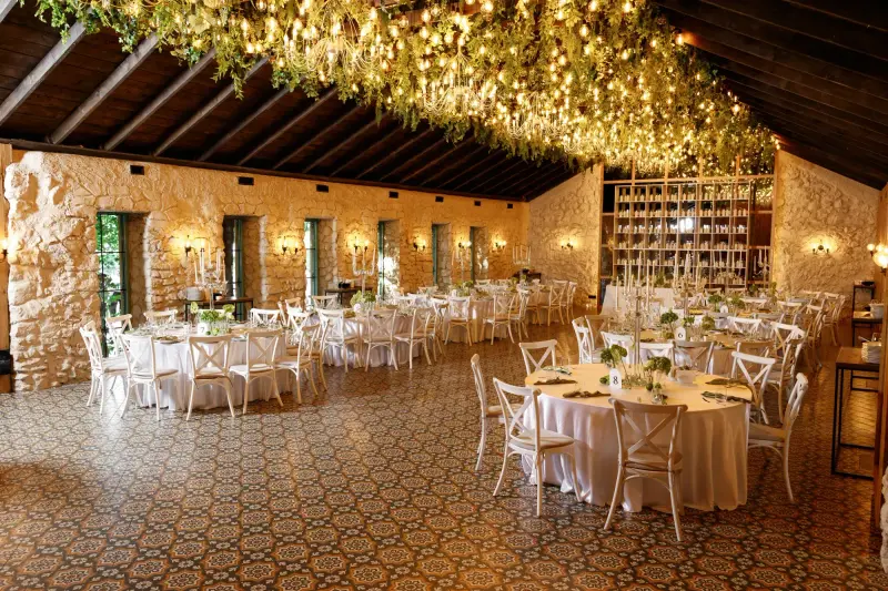 Sala Lago Event Park sub un plafon de verdeață și ghirlande luminoase, cu mese albe aranjate festiv