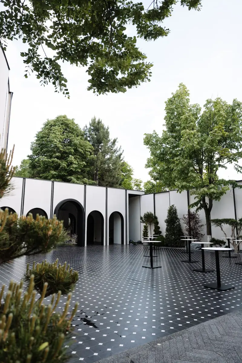Curtea Raymond Park, cu arcade albe, pardoseală neagră cu puncte albe și copaci