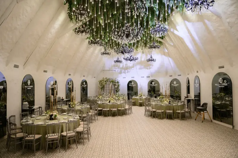 Sala Villa Garden, cu plafon de verdeață, candelabre negre și mese rotunde aranjate